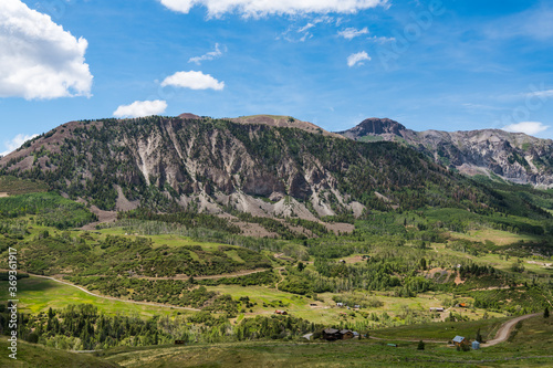 Rugged landscape of mountains  green fields  ranches  and buildings along Last Dollar Road near Telluride  Colorado