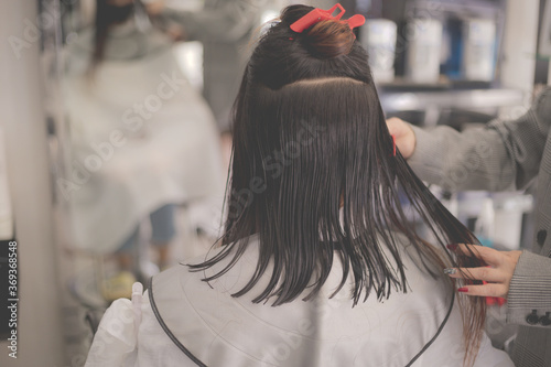 Women's haircut. Woman hairdresser making hairstyle in beauty salon. Professional stylist cutting woman's hair in salon.