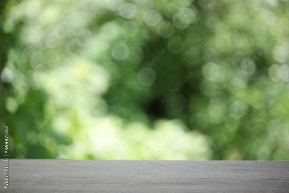 Empty wooden table top planks with beautiful nature blurred green leaf background under sunlight Empty wooden table top planks with beautiful nature blurred green leaf background under sunlight