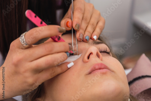 Close-up of a woman in a beauty parlor.  Several artificial eyelashes in tweezers.  Artificial eyelash extensions.  Beauty and self-care. © René Stevens