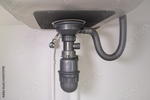 Water drain pipe under kitchen sink and faucet.
