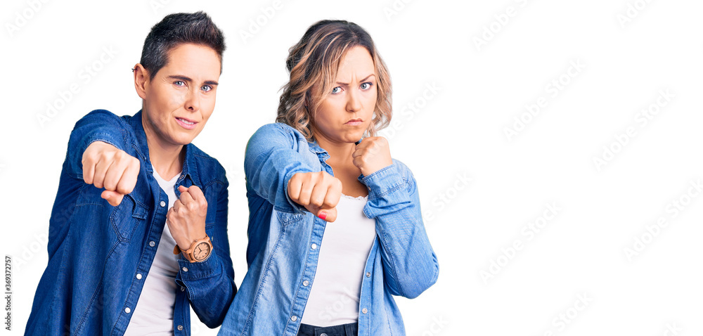 Fototapeta premium Couple of women wearing casual clothes punching fist to fight, aggressive and angry attack, threat and violence