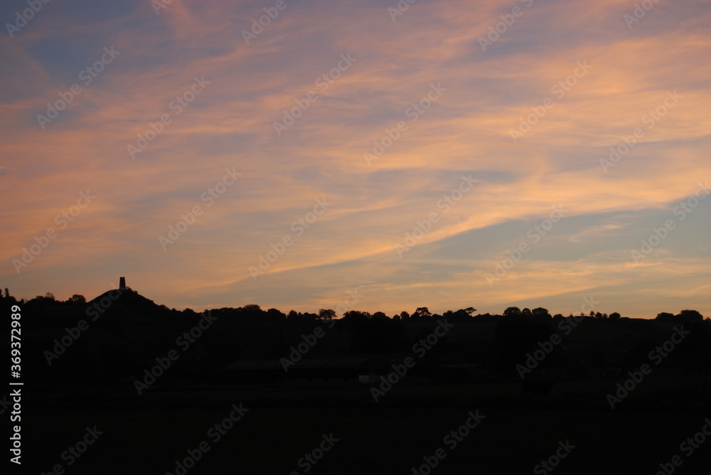 Sunrise Over Glastonbury Skyline Silhouette with Tor Orange Clouds Vivid Color Rural Countryside