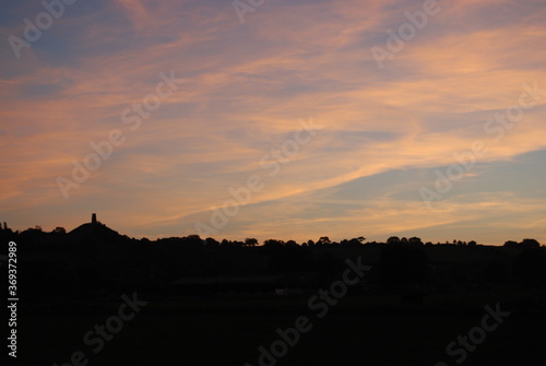 Sunrise Over Glastonbury Skyline Silhouette with Tor Orange Clouds Vivid Color Rural Countryside