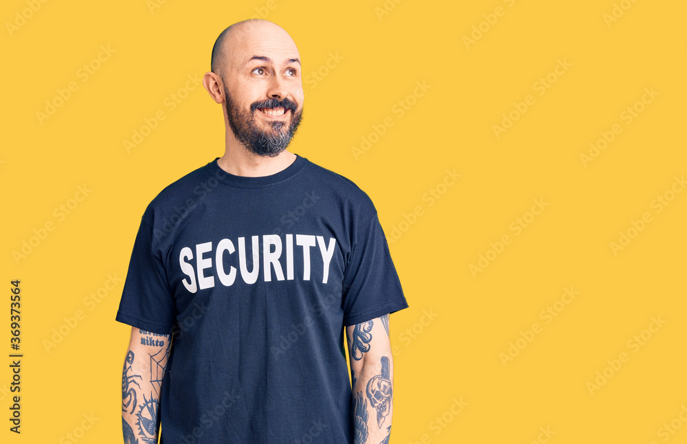 Young handsome man wearing security t shirt smiling looking to the side and staring away thinking. Young handsome man wearing security t shirt smiling looking to the side and staring away thinking.