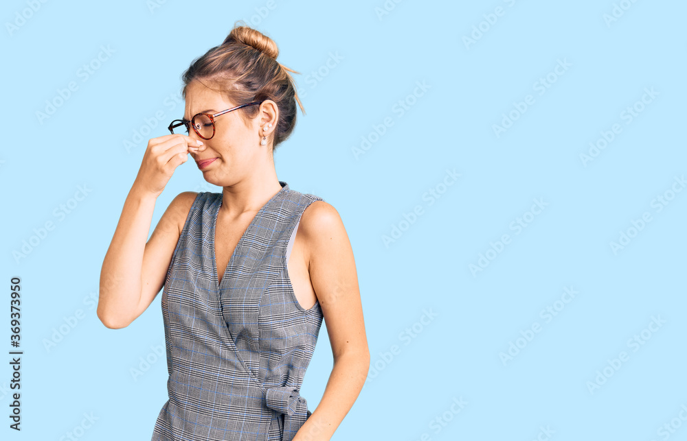 Beautiful caucasian woman with blonde hair wearing business clothes and glasses smelling something stinky and disgusting, intolerable smell, holding breath with fingers on nose. bad smell Beautiful caucasian woman with blonde hair wearing business clothes and glasses smelling something stinky and disgusting, intolerable smell, holding breath with fingers on nose. bad smell