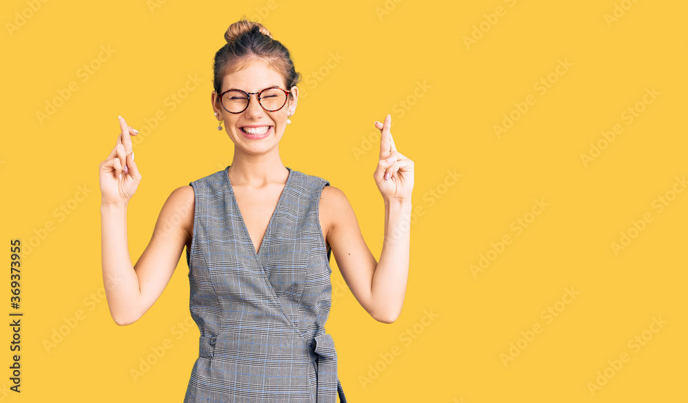 Beautiful caucasian woman with blonde hair wearing business clothes and glasses gesturing finger crossed smiling with hope and eyes closed. luck and superstitious concept. Beautiful caucasian woman with blonde hair wearing business clothes and glasses gesturing finger crossed smiling with hope and eyes closed. luck and superstitious concept.