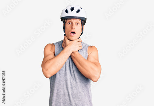 Young handsome man wearing bike helmet shouting and suffocate because painful strangle. health problem. asphyxiate and suicide concept.