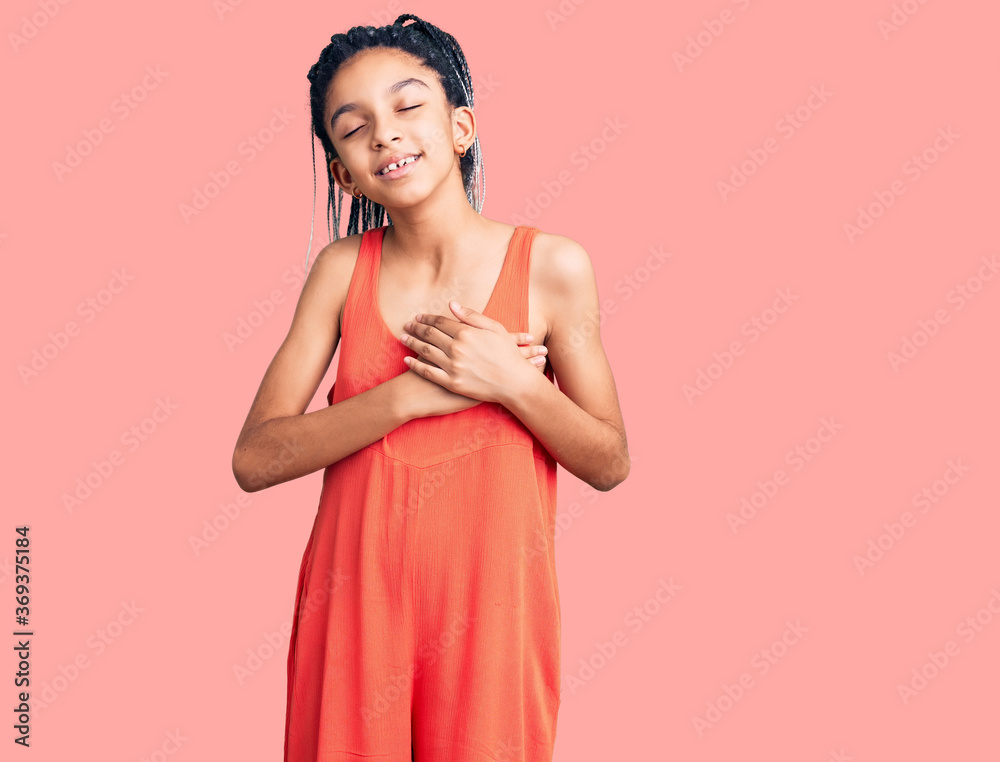 Cute african american girl wearing casual clothes smiling with hands on chest with closed eyes and grateful gesture on face. health concept. Cute african american girl wearing casual clothes smiling with hands on chest with closed eyes and grateful gesture on face. health concept.
