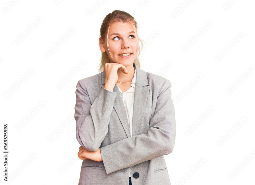 Young beautiful blonde woman wearing elegant jacket with hand on chin thinking about question, pensive expression. smiling and thoughtful face. doubt concept. Young beautiful blonde woman wearing elegant jacket with hand on chin thinking about question, pensive expression. smiling and thoughtful face. doubt concept.