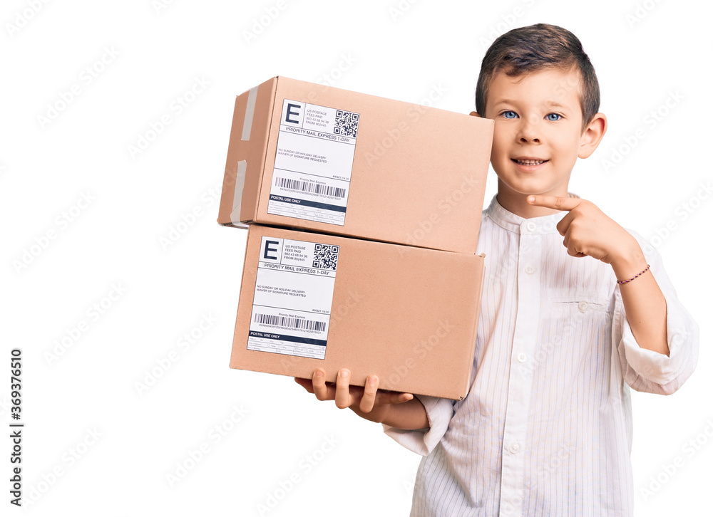 Cute blond kid holding delivery package smiling happy pointing with hand and finger Cute blond kid holding delivery package smiling happy pointing with hand and finger