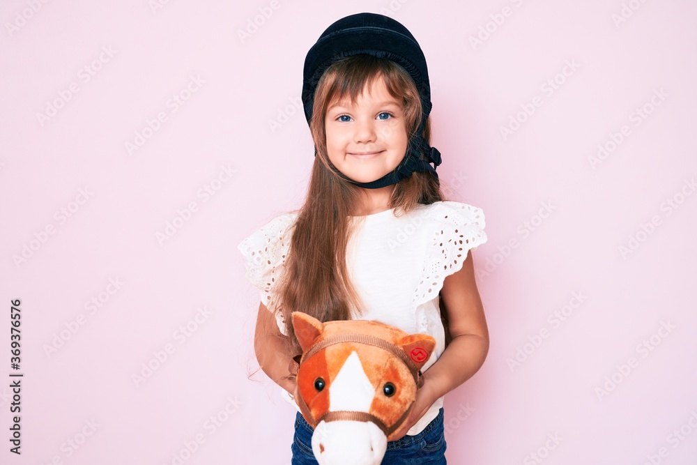 Little caucasian kid girl with long hair riding horse toy wearing ...