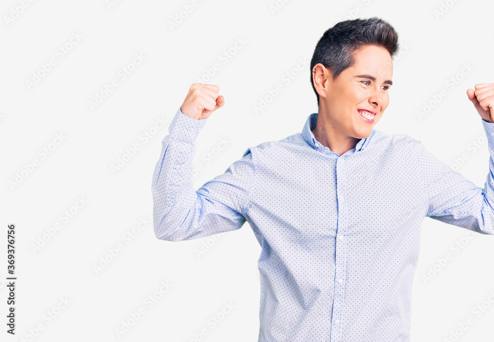 Young woman with short hair wearing business clothes showing arms muscles smiling proud. fitness concept. Young woman with short hair wearing business clothes showing arms muscles smiling proud. fitness concept.
