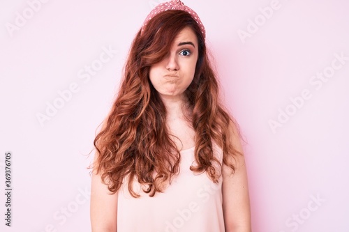 Young beautiful woman wearing casual clothes puffing cheeks with funny face. mouth inflated with air, crazy expression.
