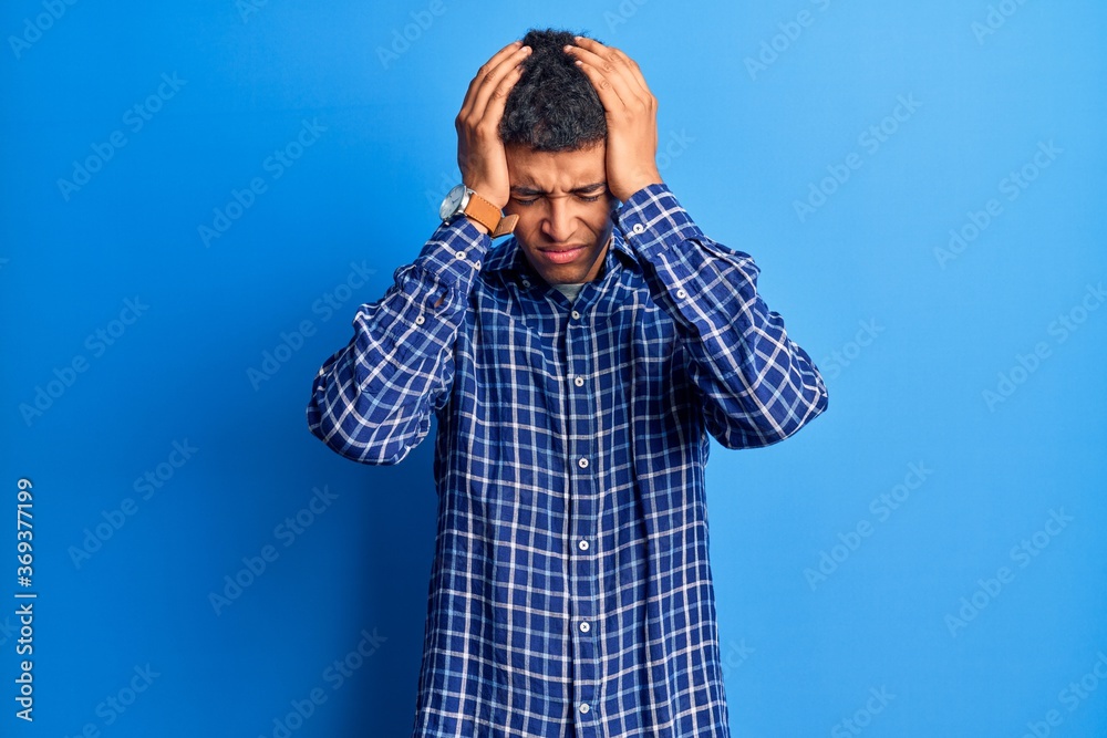 Young african amercian man wearing casual clothes suffering from headache desperate and stressed because pain and migraine. hands on head. Young african amercian man wearing casual clothes suffering from headache desperate and stressed because pain and migraine. hands on head.