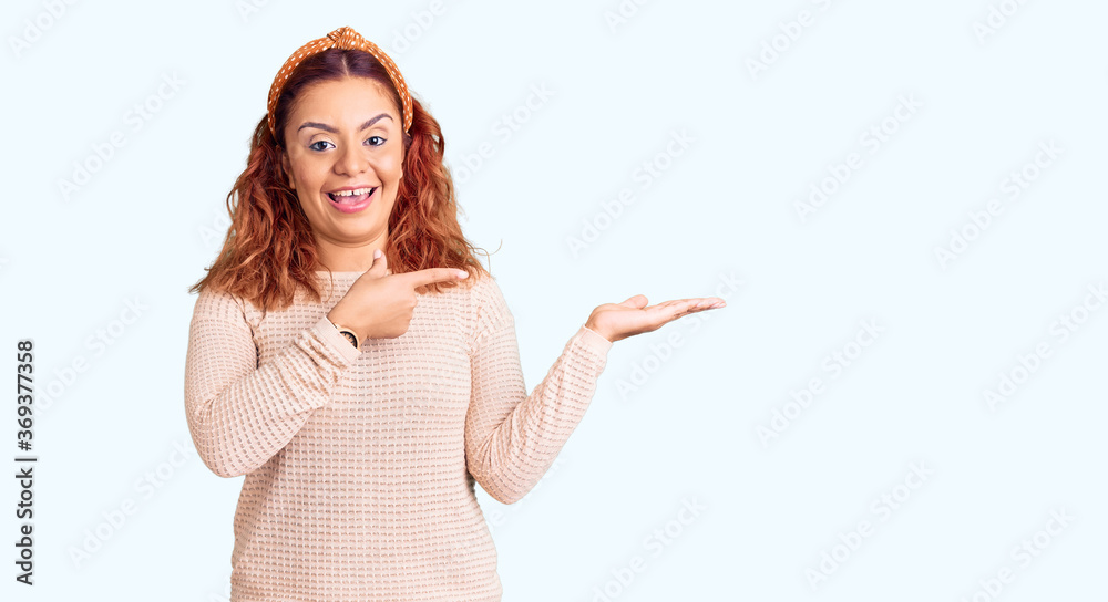 Young latin woman wearing casual clothes and diadem amazed and smiling to the camera while presenting with hand and pointing with finger. Young latin woman wearing casual clothes and diadem amazed and smiling to the camera while presenting with hand and pointing with finger.