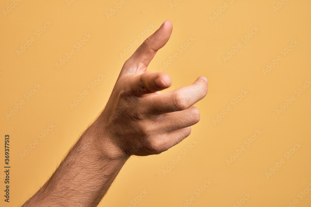 Hand of caucasian young man showing fingers over isolated yellow background pointing forefinger to the camera, choosing and indicating towards direction