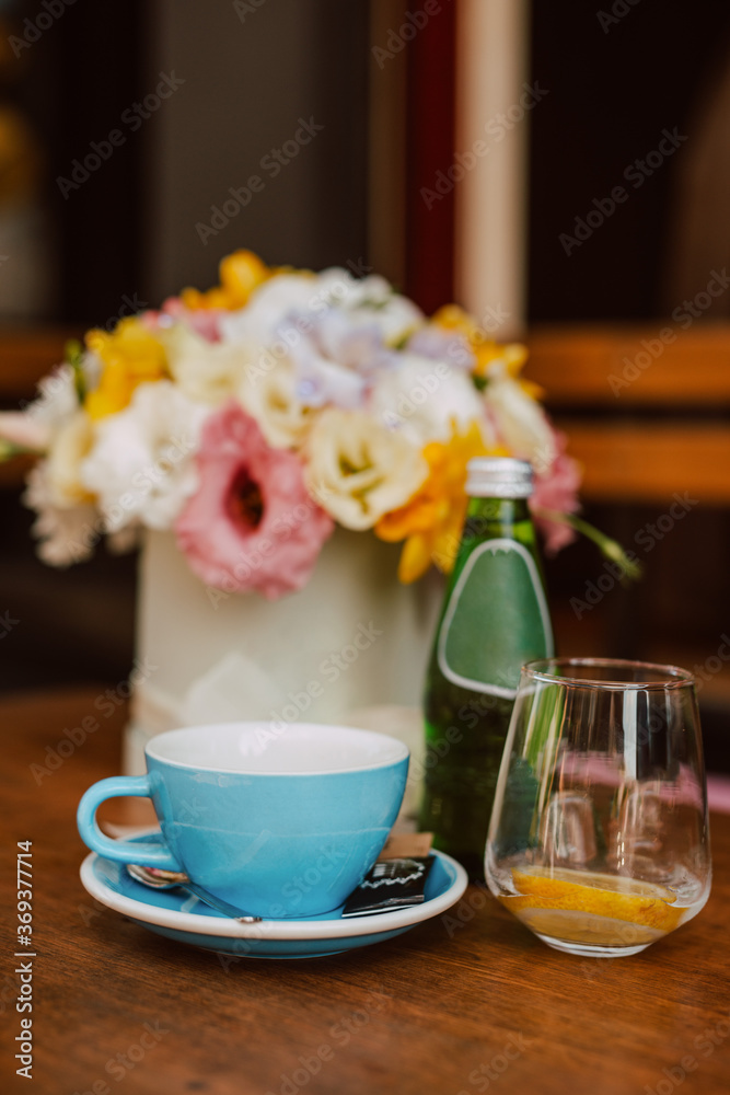 Coffee in a blue cup, sour water and flower box  on the table in the cafe