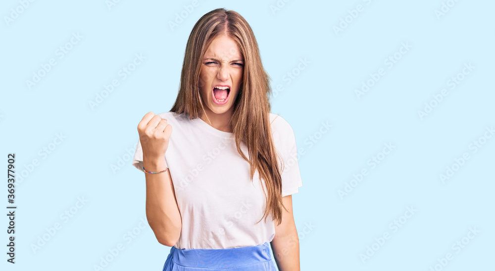 Young beautiful blonde woman wearing summer style angry and mad raising fist frustrated and furious while shouting with anger. rage and aggressive concept. Young beautiful blonde woman wearing summer style angry and mad raising fist frustrated and furious while shouting with anger. rage and aggressive concept.