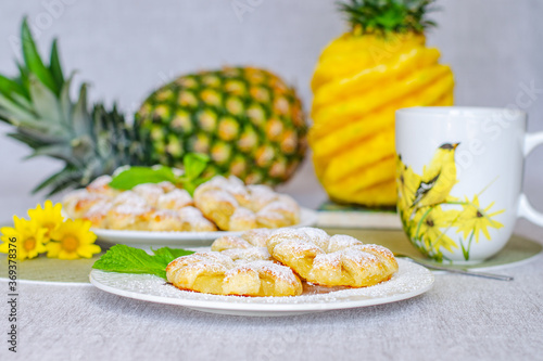 Pineapple puffs decorated with mint leaves next to tea and pineapple