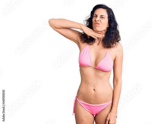 Young beautiful hispanic woman wearing bikini cutting throat with hand as knife, threaten aggression with furious violence