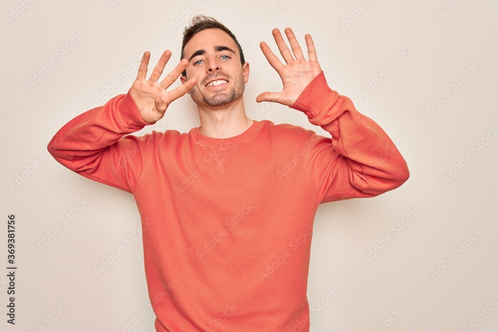 Young handsome man with blue eyes wearing casual sweater standing over white background showing and pointing up with fingers number nine while smiling confident and happy. Young handsome man with blue eyes wearing casual sweater standing over white background showing and pointing up with fingers number nine while smiling confident and happy.