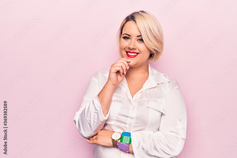 Young beautiful blonde plus size woman wearing elegant shirt over isolated pink background smiling looking confident at the camera with crossed arms and hand on chin. Thinking positive. Young beautiful blonde plus size woman wearing elegant shirt over isolated pink background smiling looking confident at the camera with crossed arms and hand on chin. Thinking positive.