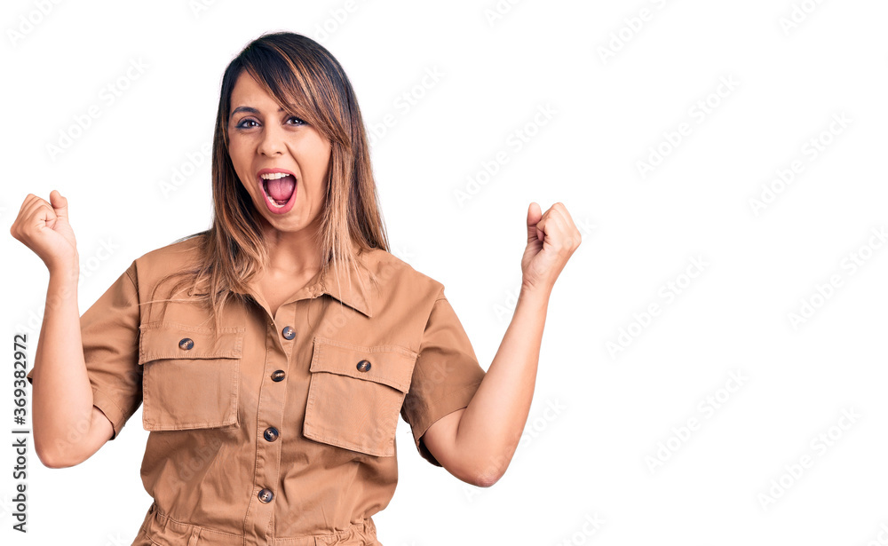 Young beautiful woman wearing casual dress screaming proud, celebrating victory and success very excited with raised arms Young beautiful woman wearing casual dress screaming proud, celebrating victory and success very excited with raised arms