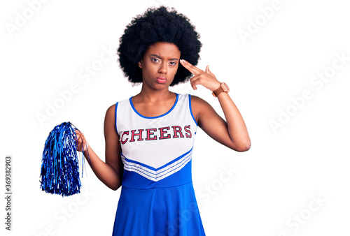 Foto Young african american woman wearing cheerleader uniform holding pompom shooting and killing oneself pointing hand and fingers to head like gun, suicide gesture