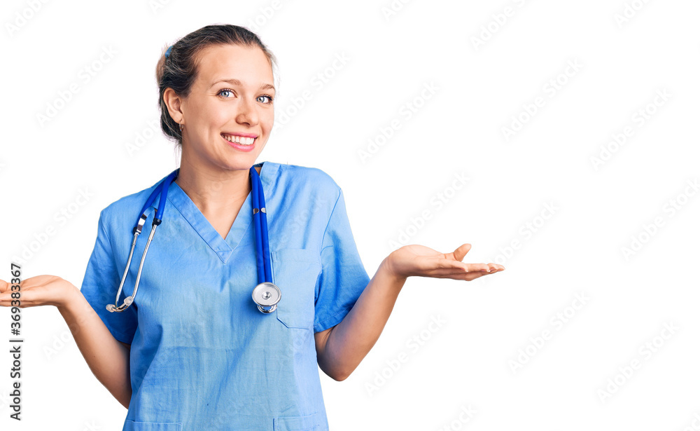 Young beautiful blonde woman wearing doctor uniform and stethoscope clueless and confused expression with arms and hands raised. doubt concept. Young beautiful blonde woman wearing doctor uniform and stethoscope clueless and confused expression with arms and hands raised. doubt concept.