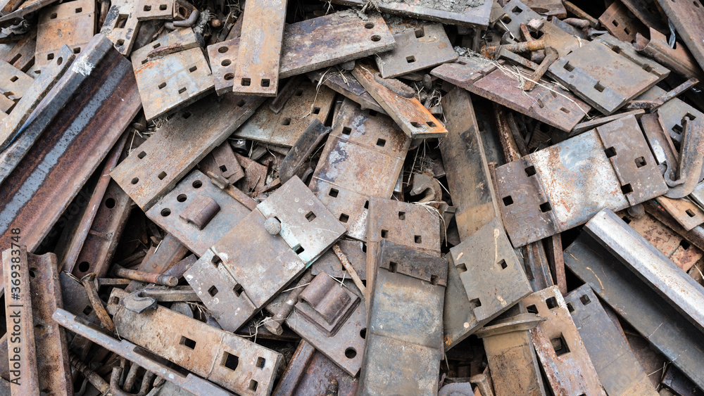 Pile of scrap metal pieces and old rusting railroad ties background. Grungy plates and rusty metal in abandoned pile