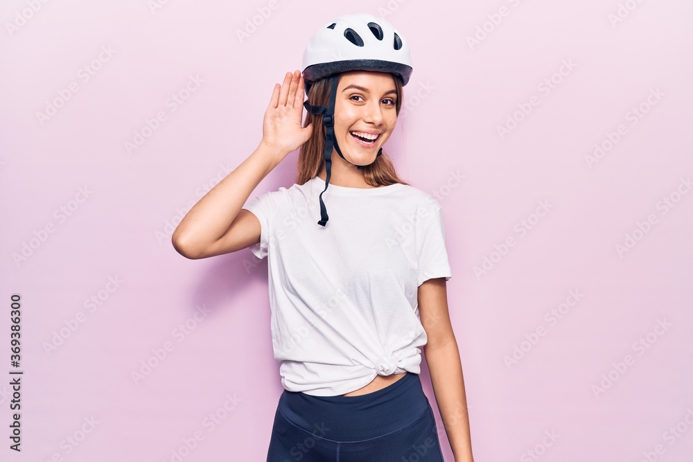 Young beautiful girl wearing bike helmet smiling with hand over ear listening and hearing to rumor or gossip. deafness concept.