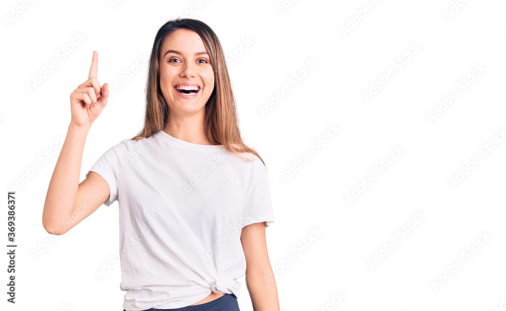 Young beautiful girl wearing casual t shirt pointing finger up with successful idea. exited and happy. number one. Young beautiful girl wearing casual t shirt pointing finger up with successful idea. exited and happy. number one.