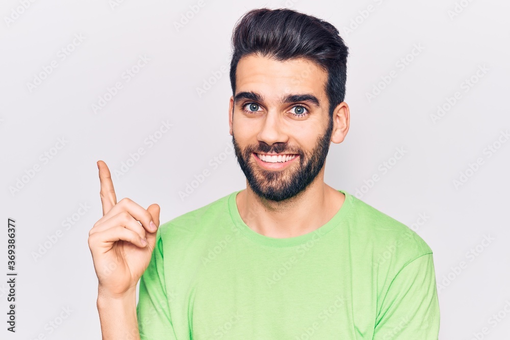 Young handsome man with beard wearing casual t-shirt smiling happy pointing with hand and finger to the side Young handsome man with beard wearing casual t-shirt smiling happy pointing with hand and finger to the side