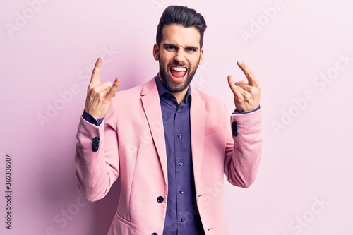 Fotografia Young handsome man with beard wearing elegant jacket shouting with crazy expression doing rock symbol with hands up