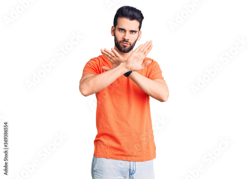 Young handsome man with beard wearing casual t-shirt rejection expression crossing arms doing negative sign, angry face