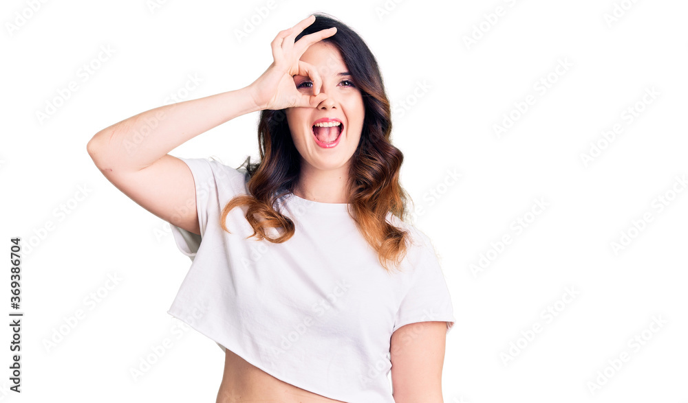 Beautiful young brunette woman wearing casual clothes smiling happy doing ok sign with hand on eye looking through fingers Beautiful young brunette woman wearing casual clothes smiling happy doing ok sign with hand on eye looking through fingers