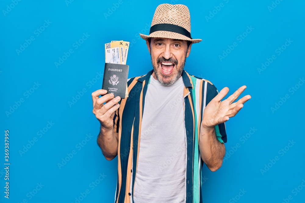 Middle age tourist man on vacation holding united states passport with boarding pass celebrating achievement with happy smile and winner expression with raised hand Middle age tourist man on vacation holding united states passport with boarding pass celebrating achievement with happy smile and winner expression with raised hand