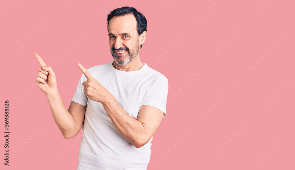 Middle age handsome man wearing casual t-shirt smiling and looking at the camera pointing with two hands and fingers to the side. Middle age handsome man wearing casual t-shirt smiling and looking at the camera pointing with two hands and fingers to the side.