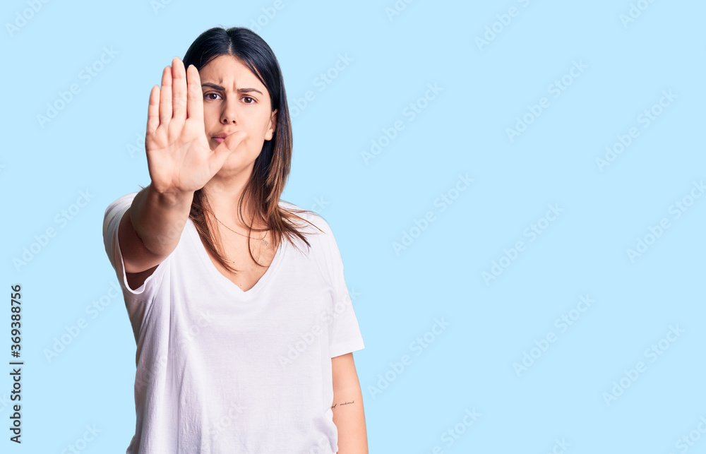 Young beautiful brunette woman wearing casual t-shirt doing stop sing with palm of the hand. warning expression with negative and serious gesture on the face. Young beautiful brunette woman wearing casual t-shirt doing stop sing with palm of the hand. warning expression with negative and serious gesture on the face.