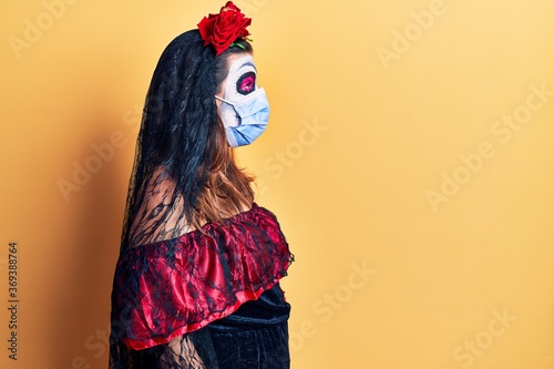 Young woman wearing day of the dead costume wearing medical mask looking to side, relax profile pose with natural face with confident smile.
