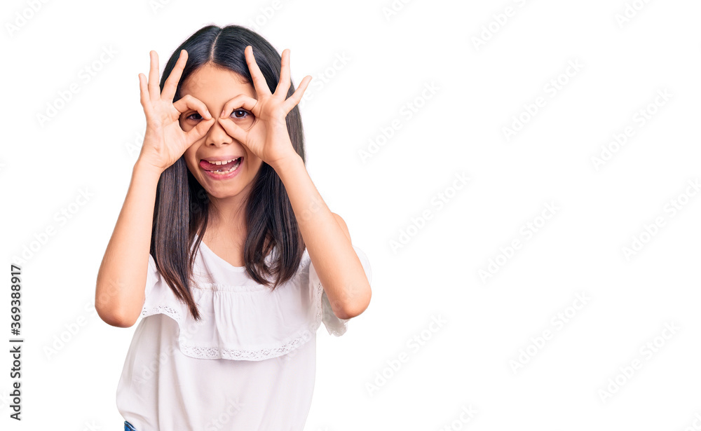 Beautiful child girl wearing casual clothes doing ok gesture like binoculars sticking tongue out, eyes looking through fingers. crazy expression. Beautiful child girl wearing casual clothes doing ok gesture like binoculars sticking tongue out, eyes looking through fingers. crazy expression.