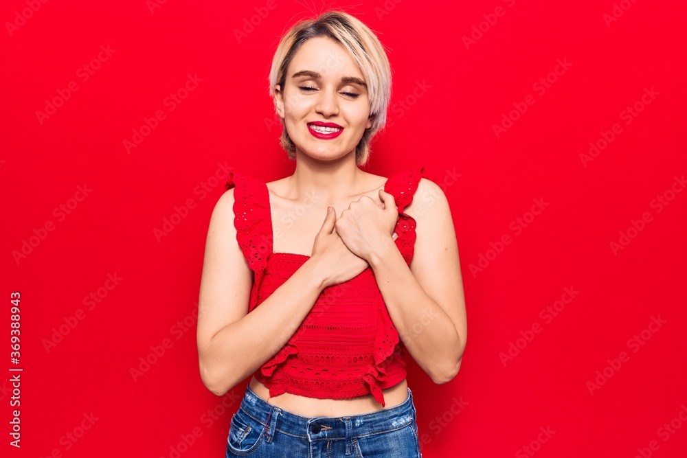 Young beautiful blonde woman wearing casual clothes smiling with hands on chest with closed eyes and grateful gesture on face. health concept. Young beautiful blonde woman wearing casual clothes smiling with hands on chest with closed eyes and grateful gesture on face. health concept.