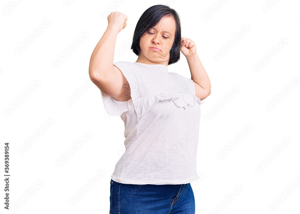Brunette woman with down syndrome wearing casual white tshirt showing arms muscles smiling proud. fitness concept. Brunette woman with down syndrome wearing casual white tshirt showing arms muscles smiling proud. fitness concept.