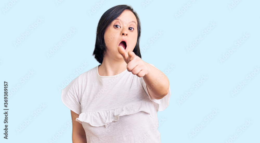Brunette woman with down syndrome wearing casual white tshirt pointing displeased and frustrated to the camera, angry and furious with you