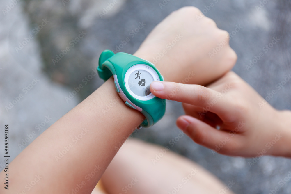 Fototapeta premium Close up Girl using smartwatch touching button and touchscreen on active sports. Finger touch button on smarth watch. Girl set smart watch before running on road.