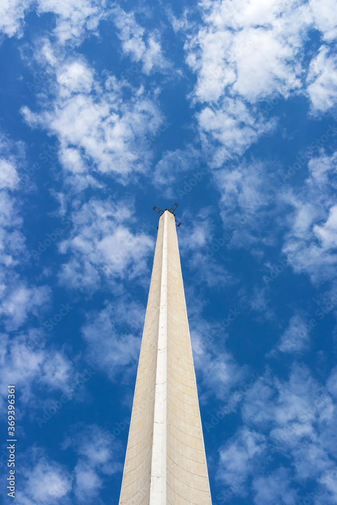 the concrete spire of the antenna rises up against the blue sky