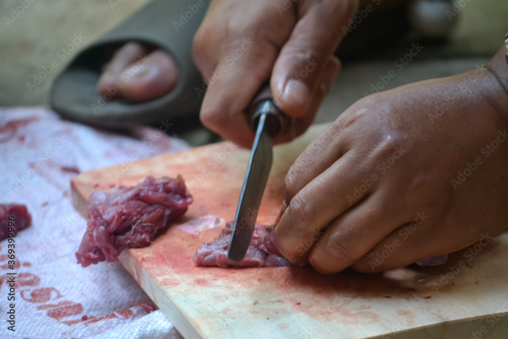 close up. someone was cutting meat using a knife on a wooden board.