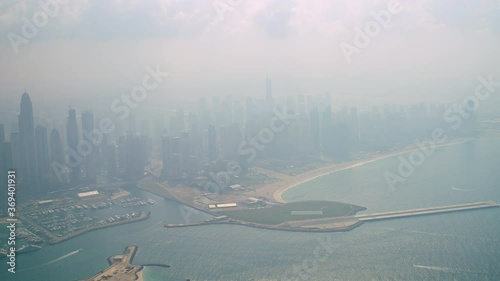 A coastline view of Skydive Dubai and its take off platform surrounded by the skyline of Dubai Marina, tilt up to down, 6-axis stabilized gimbal, Shotover F1, 8K. photo