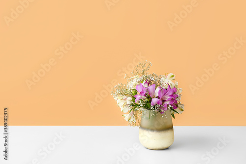 Beautiful vase with flowers on table against color background © Pixel-Shot
